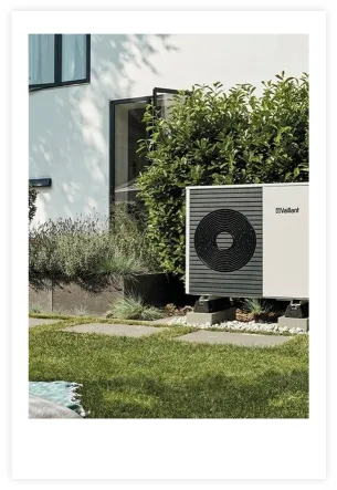 Image of a Vaillant heat pump in front of a house with grass in the foreground